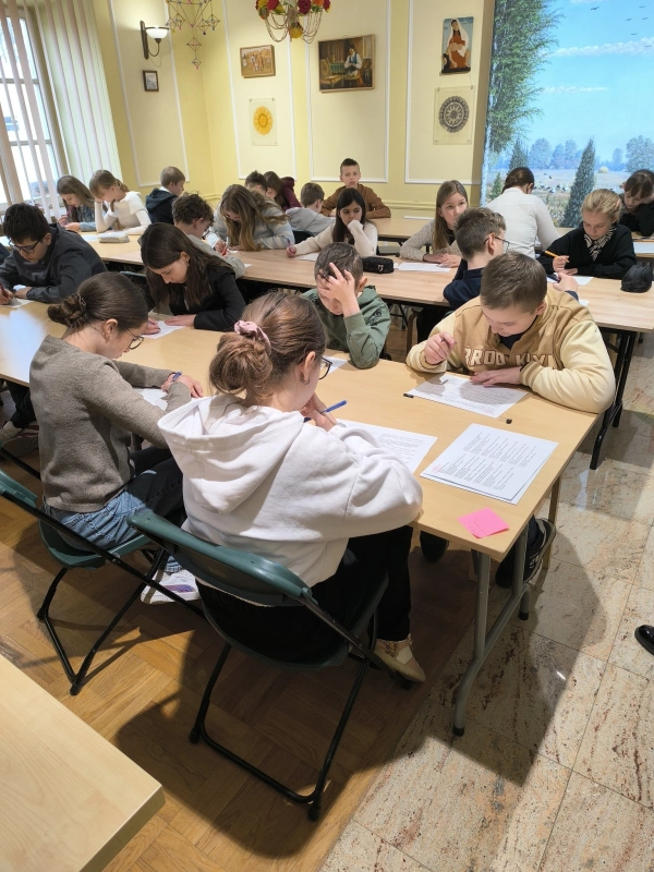 Uczniowie siedzą przy stołach; skupiona praca indywidualna.