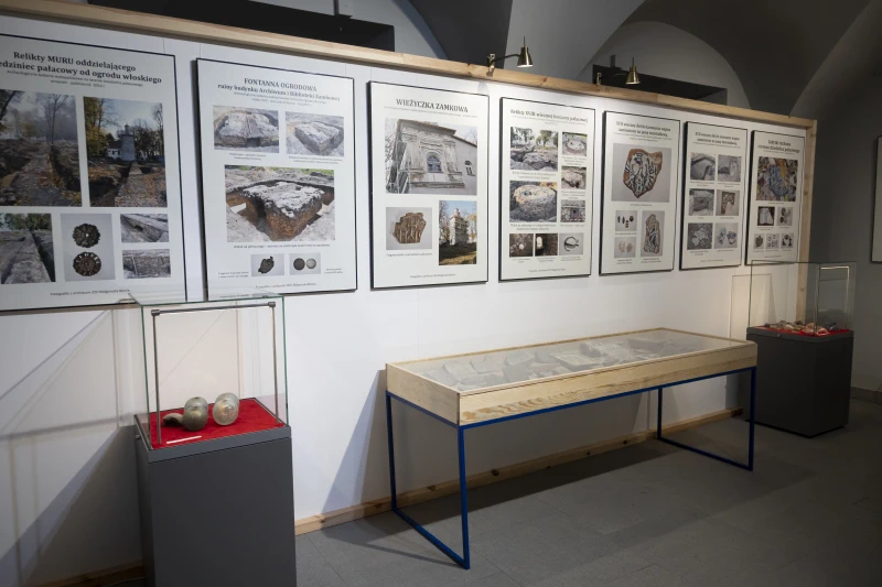 „Wnętrze wystawy historycznej z eksponatami w szklanych gablotach i materiałami informacyjnymi dotyczącymi odkryć archeologicznych.”