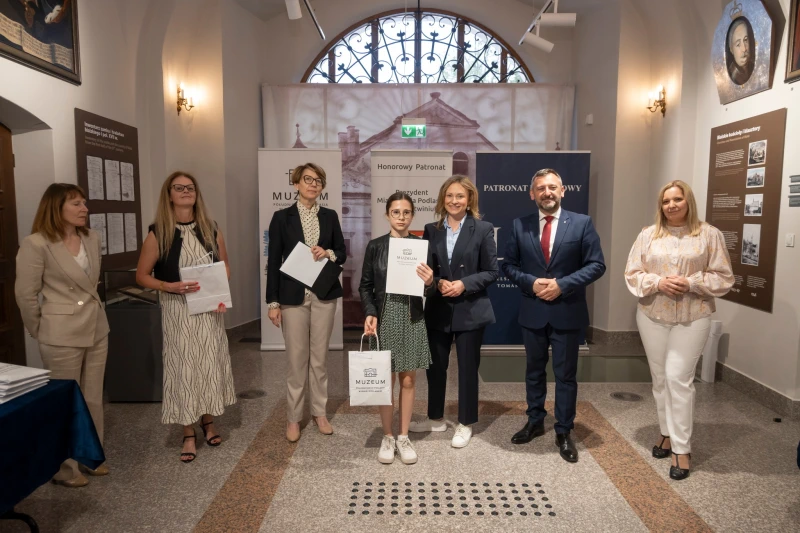 Wręczenie nagrody uczestnikowi konkursu w sali muzealnej.