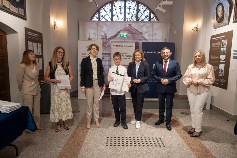 Wręczenie nagrody uczestnikowi konkursu w sali muzealnej.