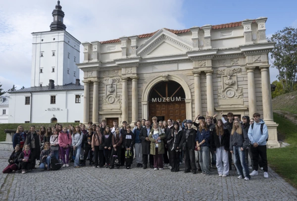 Uczestnicy warzsztatow na tle bramy jwazdowej w parku radziwiłła