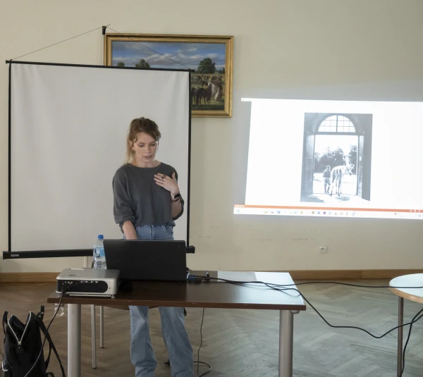 Osoba prowadzi prezentację przed grupą, a na ekranie wyświetlone jest zdjęcie konia.